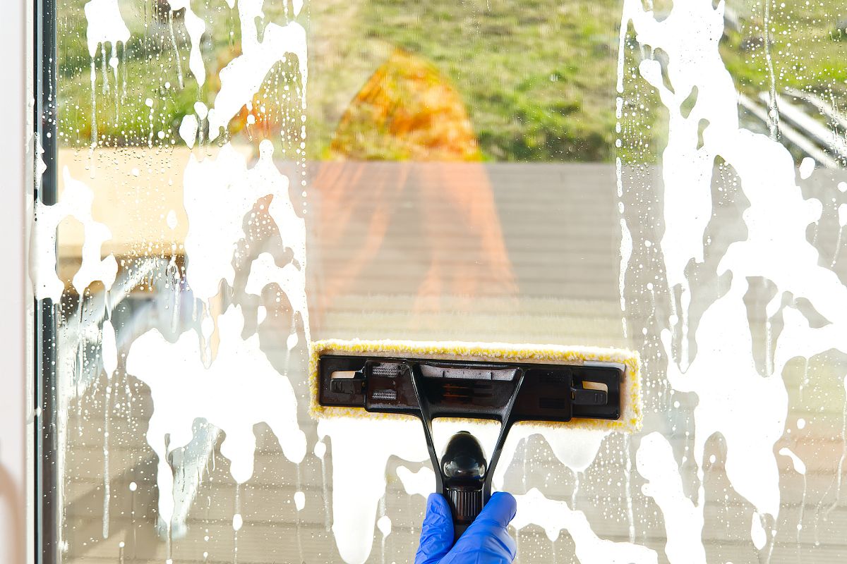  An individual in blue gloves is seen cleaning a window with a squeegee, demonstrating effective window maintenance. 