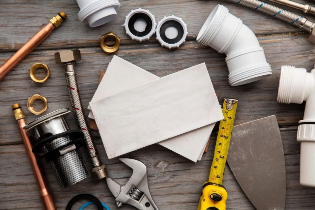 A collection of plumbing tools and materials on a wooden table, showcasing wrenches, pipes, and other plumbing essentials.