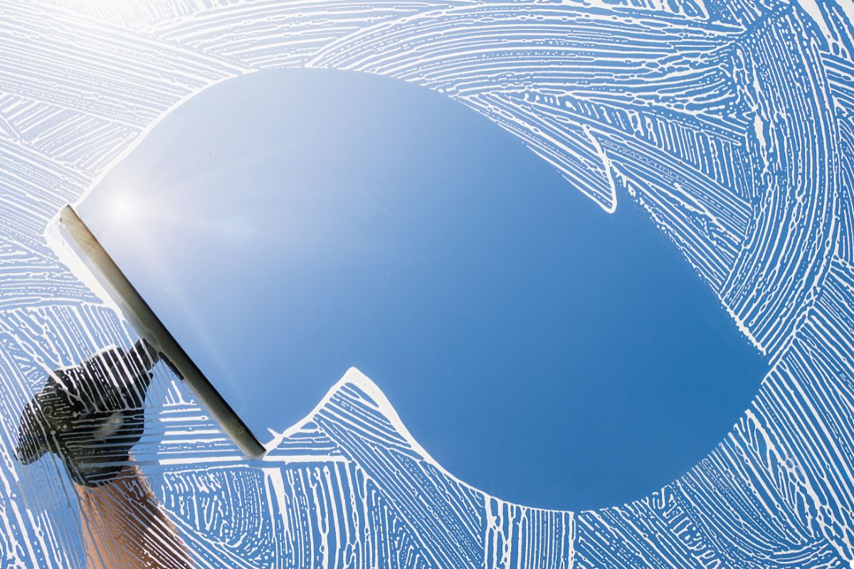 A person cleaning a window with a squeegee, demonstrating effective window maintenance techniques. 